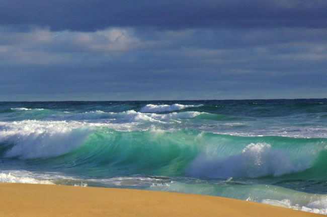 The lit up turquoise breakers under the lowering blue-grey skies make this a dramatic picture. Near Wonthaggi, Victoria, Australia.